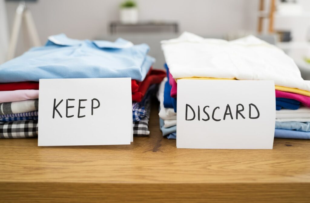 Two piles of clothing being sorted for either keeping or discarding in order to declutter and purge