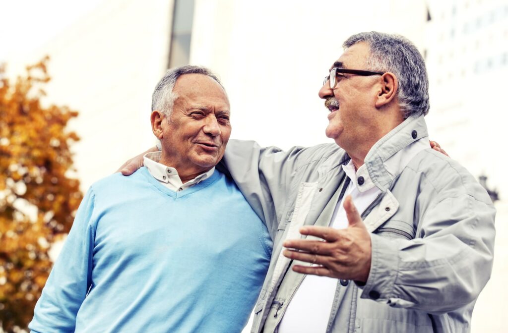 Two mature men walking and laughing as they each have one arm around the other