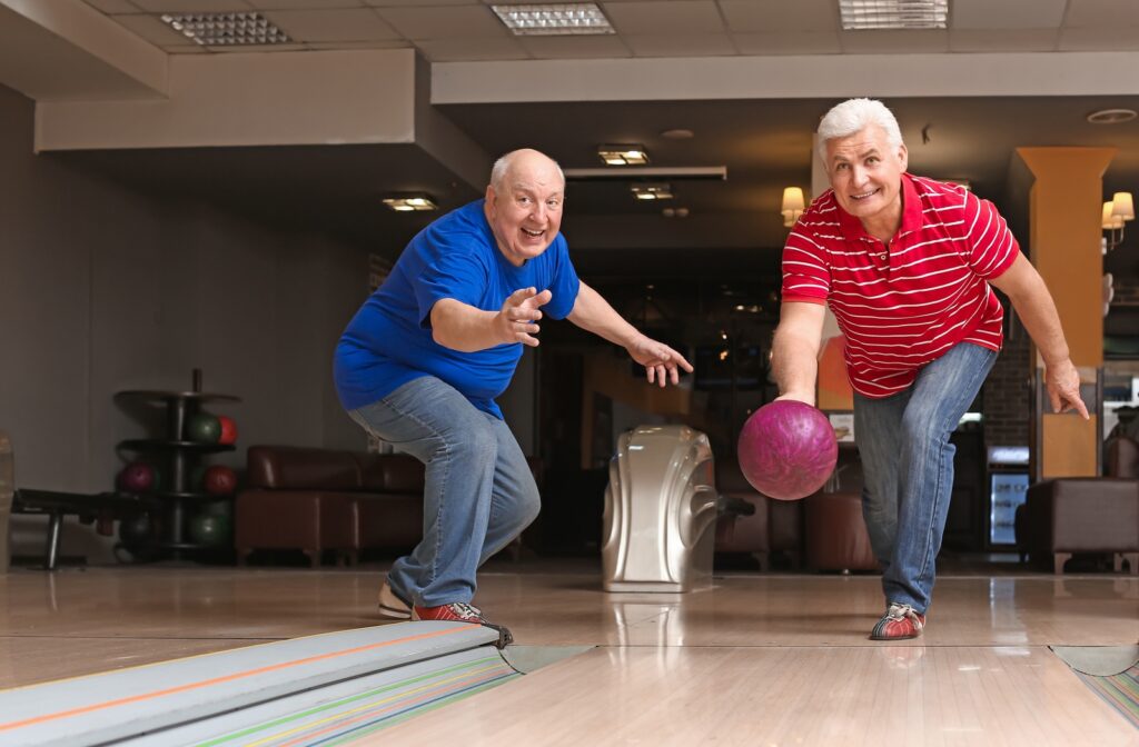 Two mature men having fun at the bowling alley.