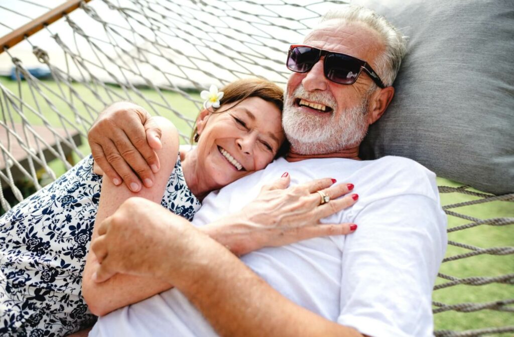 A senior couple on vacation embrace as they lay together in a hammock.