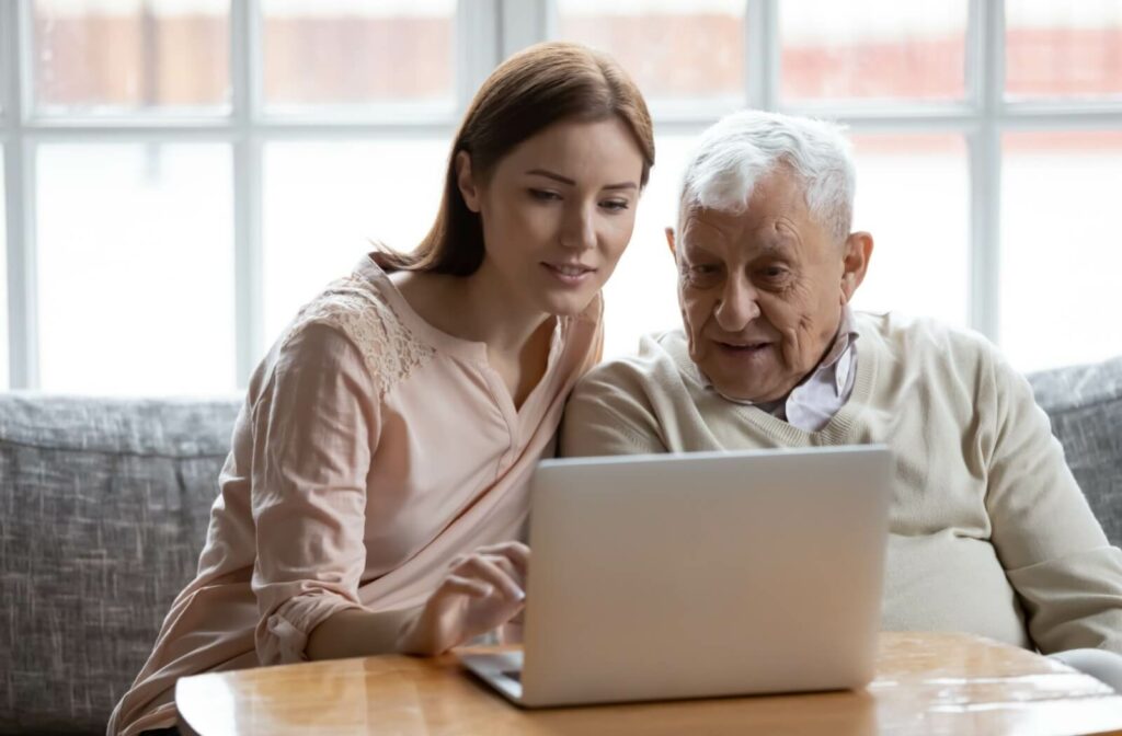 An older adult listening while their adult child teaches them how to use their new laptop safely when going online.