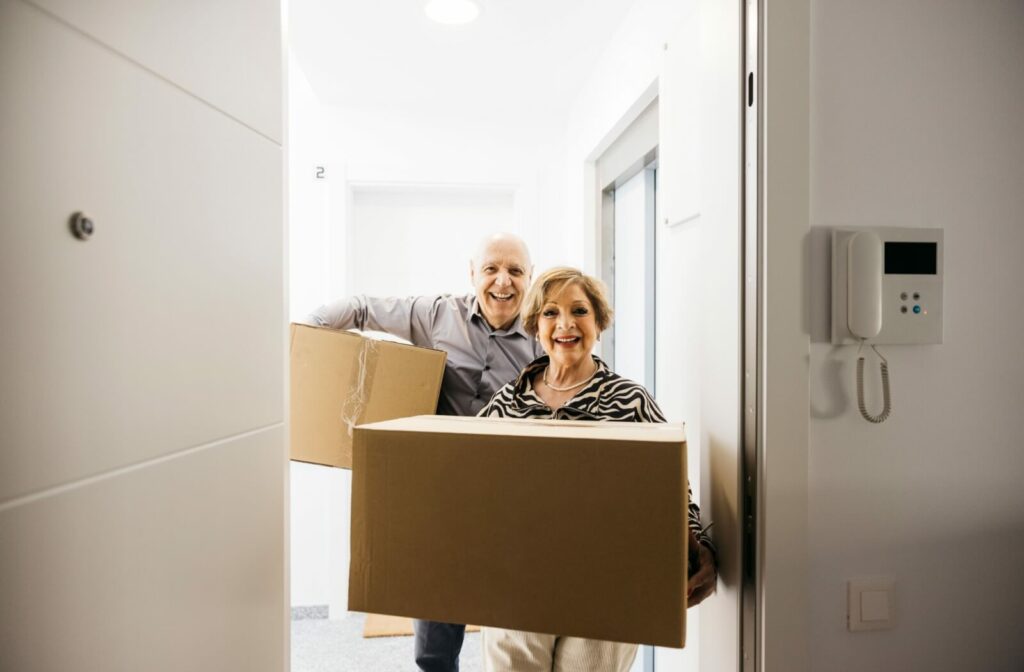A senior couple carry boxes into their new independent living home, excited to start he next leg of their life’s journey