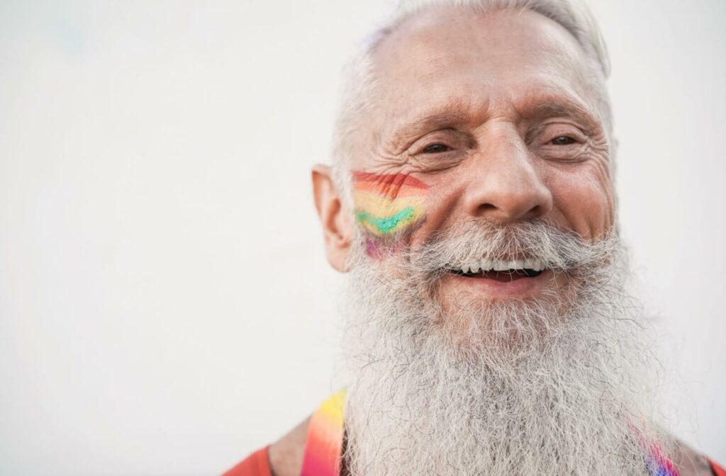 senior with a pride flag painted on their cheek and smiling proudly