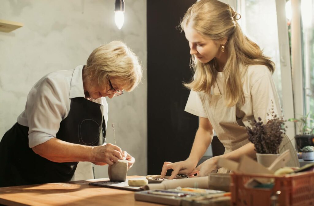 A teacher assists a senior making a design in a pottery class.