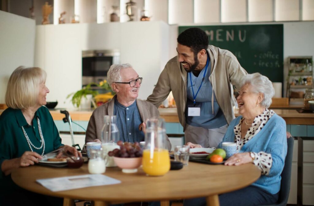 A caregiver checks on three older residents in independent living while they eat their breakfast