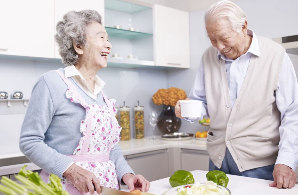 A senior couple chop vegetables as they prepare a meal in their independent living apartment
